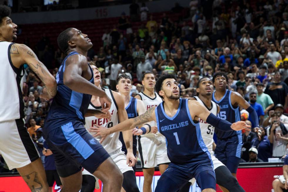 Members of the Memphis Grizzlies and Miami Heat watch the final shot go through the net, sealin ...