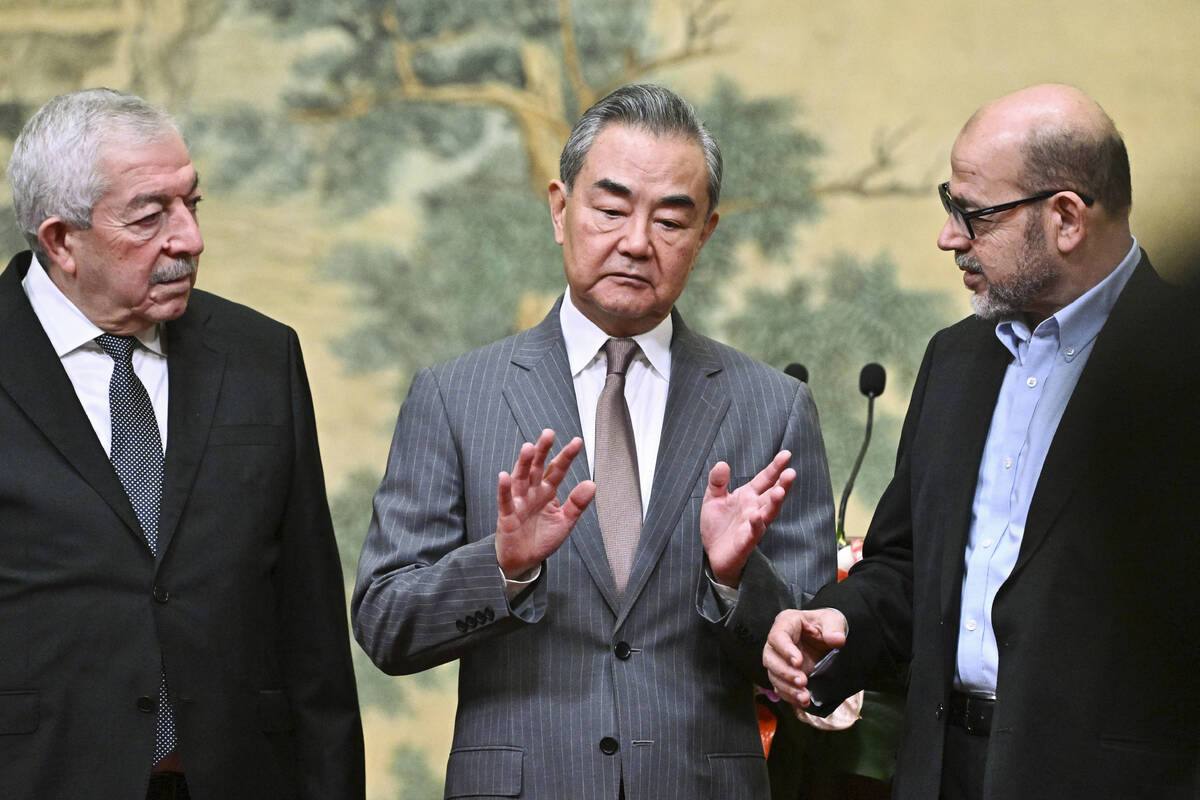 China's Foreign Minister Wang Yi, center, hosts an event for Mahmoud al-Aloul, left, vice chair ...