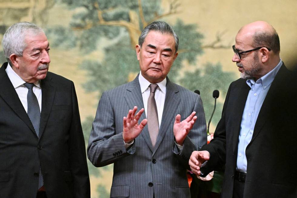 China's Foreign Minister Wang Yi, center, hosts an event for Mahmoud al-Aloul, left, vice chair ...