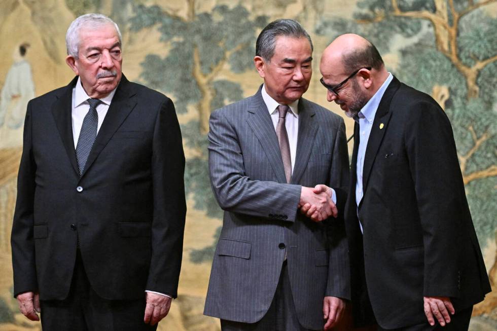 China's Foreign Minister Wang Yi, center, hosts an event for Mahmoud al-Aloul, left, vice chair ...