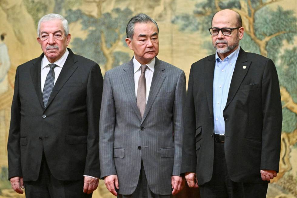 China's Foreign Minister Wang Yi, center, hosts an event for Mahmoud al-Aloul, left, vice chair ...