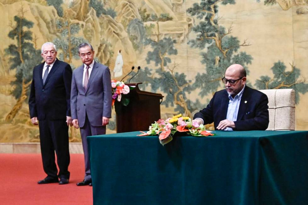 Mussa Abu Marzuk, a senior member of Hamas, right, signs a document as China's Foreign Minister ...