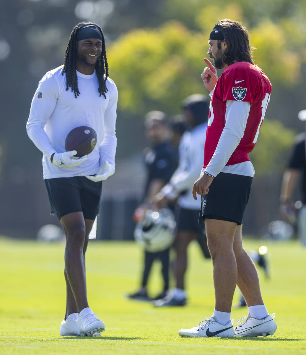 Raiders wide receiver Davante Adams (17) talks with quarterback Gardner Minshew (15) during the ...