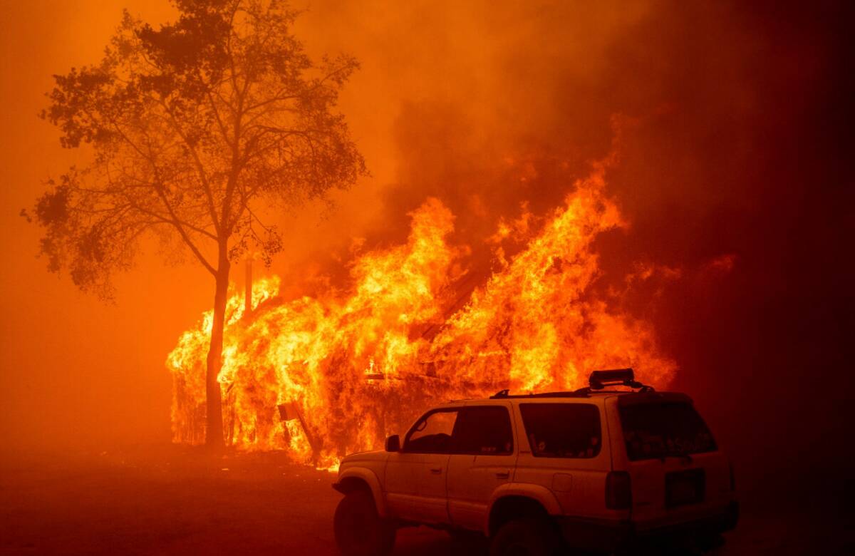 Flames consume a building as the Park Fire tears through the Cohasset community in Butte County ...