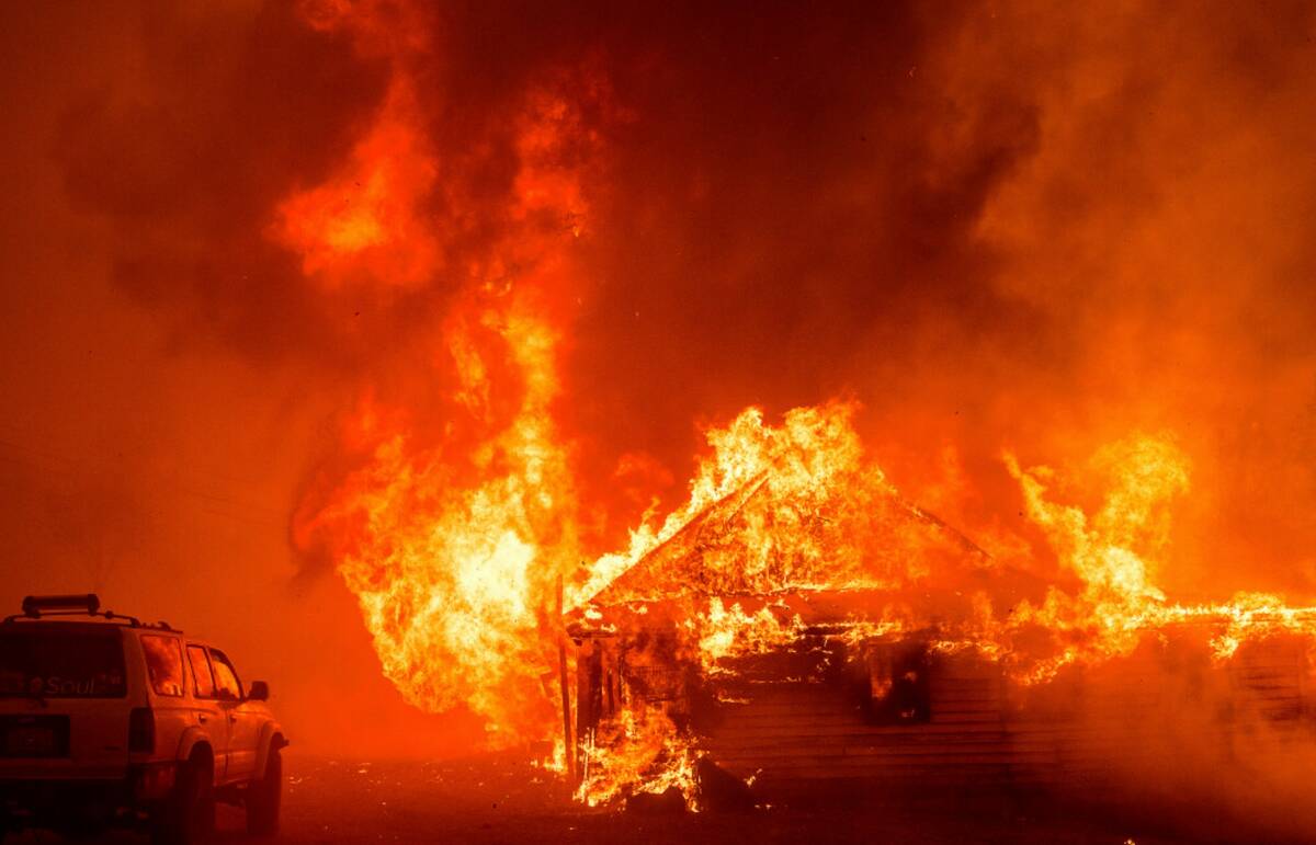 Flames consume a building as the Park Fire tears though the Cohasset community in Butte County, ...
