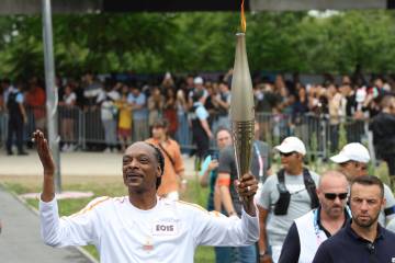 Snoop Dogg carries the Olympic torch at the 2024 Summer Olympics, Friday, July 26, 2024, in Sai ...