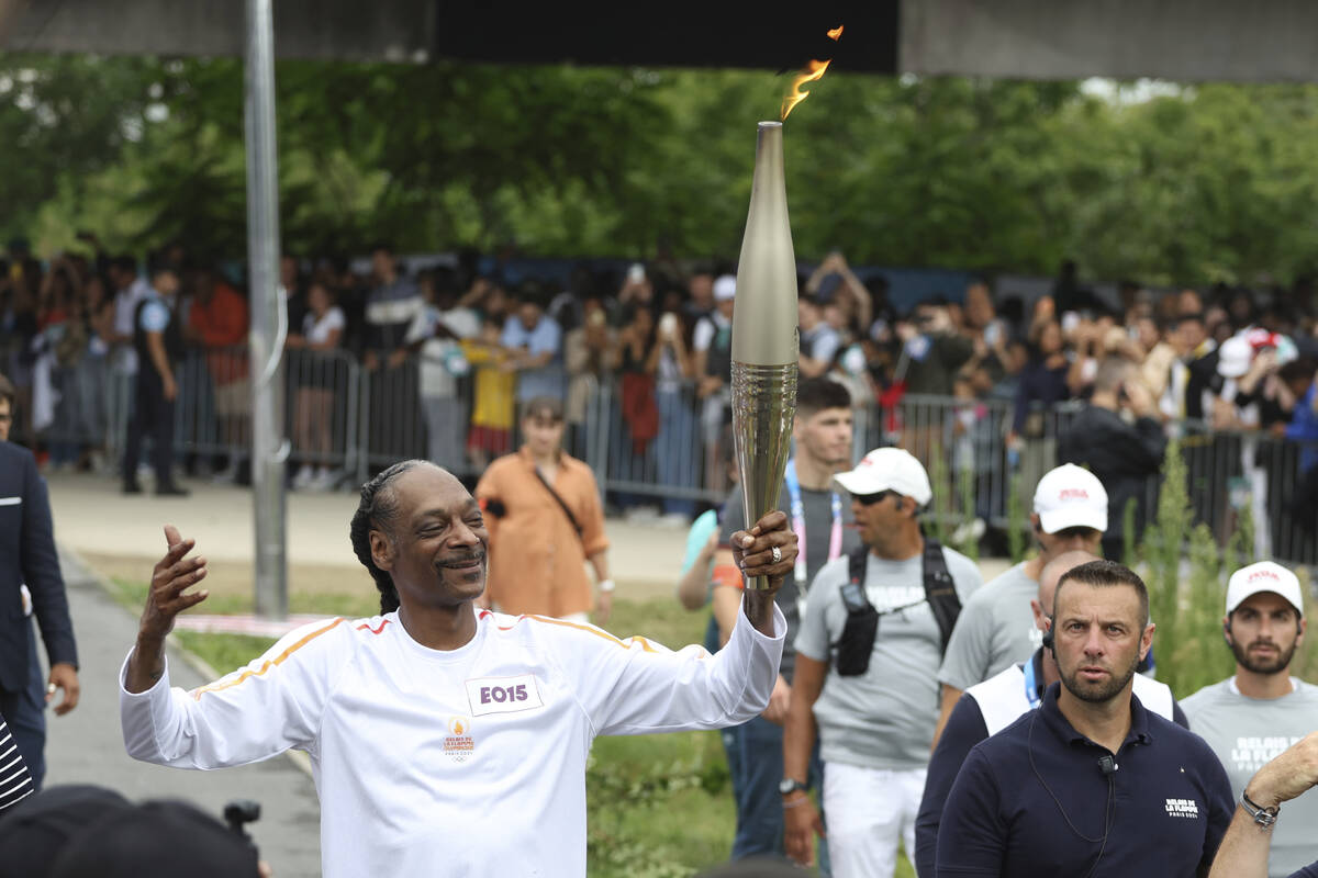 Snoop Dogg carries the Olympic torch at the 2024 Summer Olympics, Friday, July 26, 2024, in Sai ...