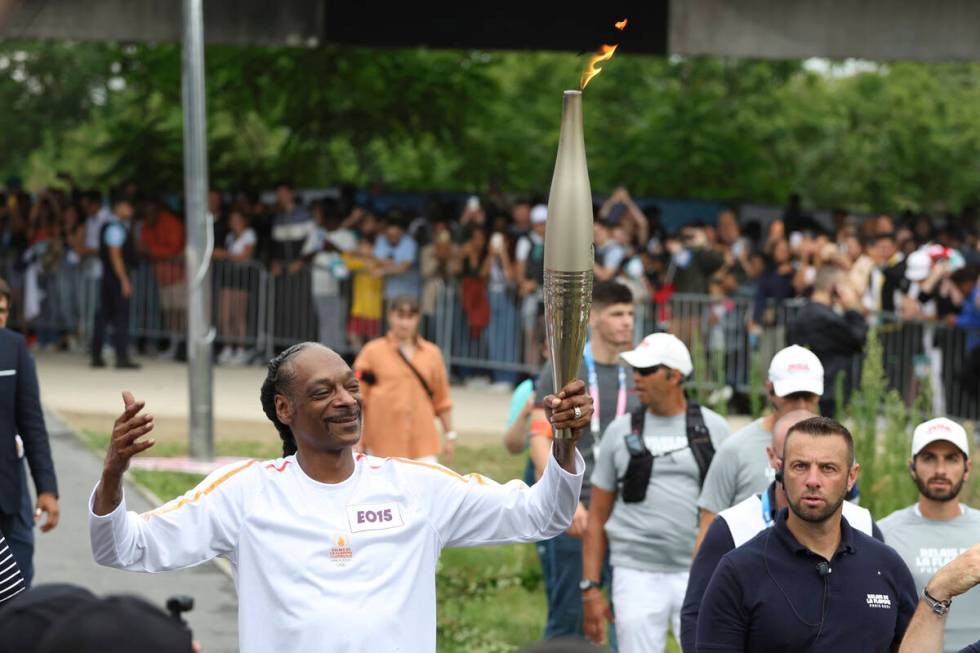 Snoop Dogg carries the Olympic torch at the 2024 Summer Olympics, Friday, July 26, 2024, in Sai ...