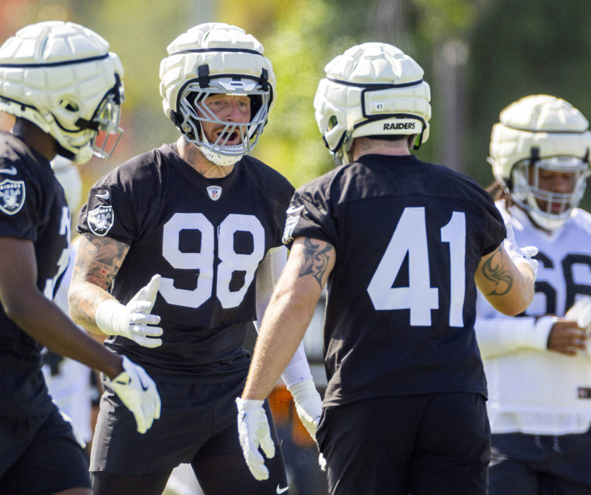 Raiders defensive end Maxx Crosby (98) gets pumped up with linebacker Robert Spillane (41) duri ...