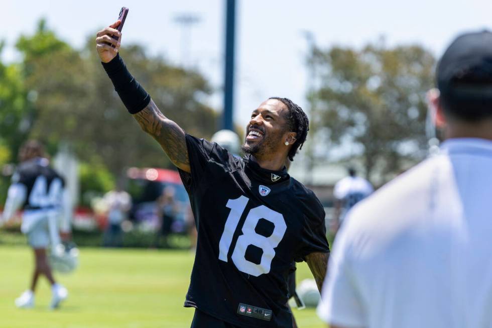 Raiders cornerback Jack Jones (18) takes a selfie with fans in the background on the way to a m ...