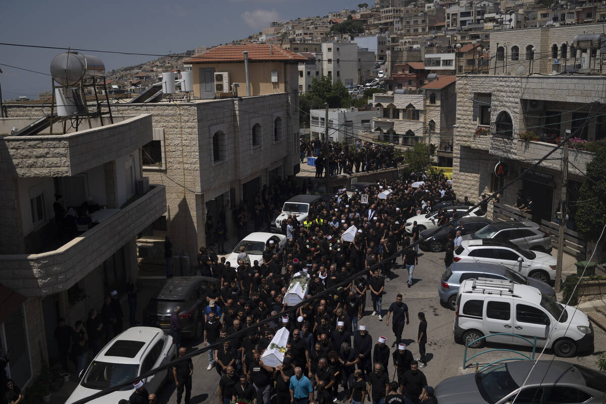 Mourners from the Druze minority carry the coffins of some of the 12 children and teens killed ...