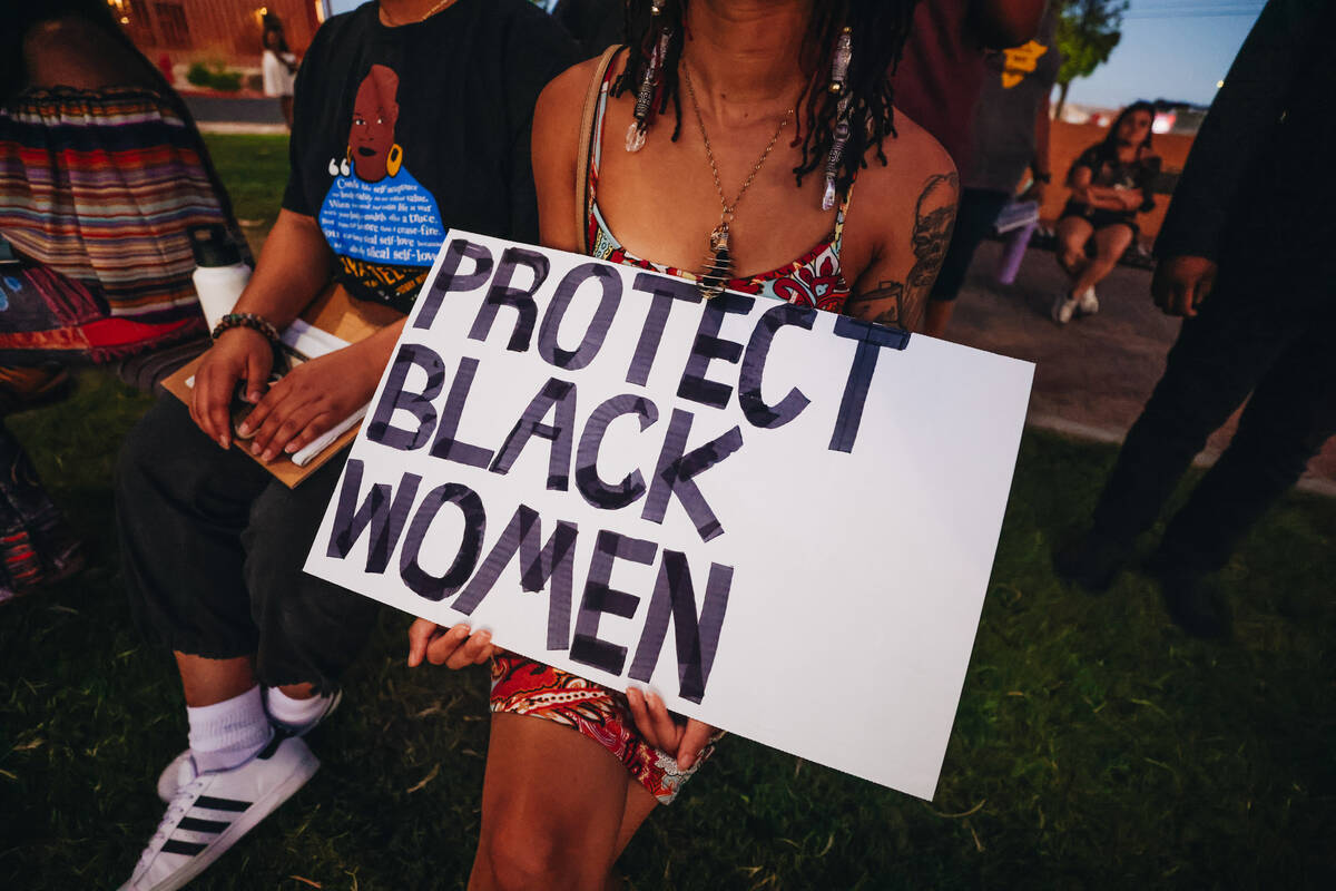 A mourner holds onto a sign that reads “Protect Black Women” during a vigil for S ...