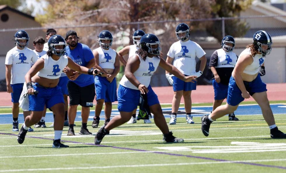 Desert Pines head coach Jose Flores, second left, watches as his players run through defensive ...