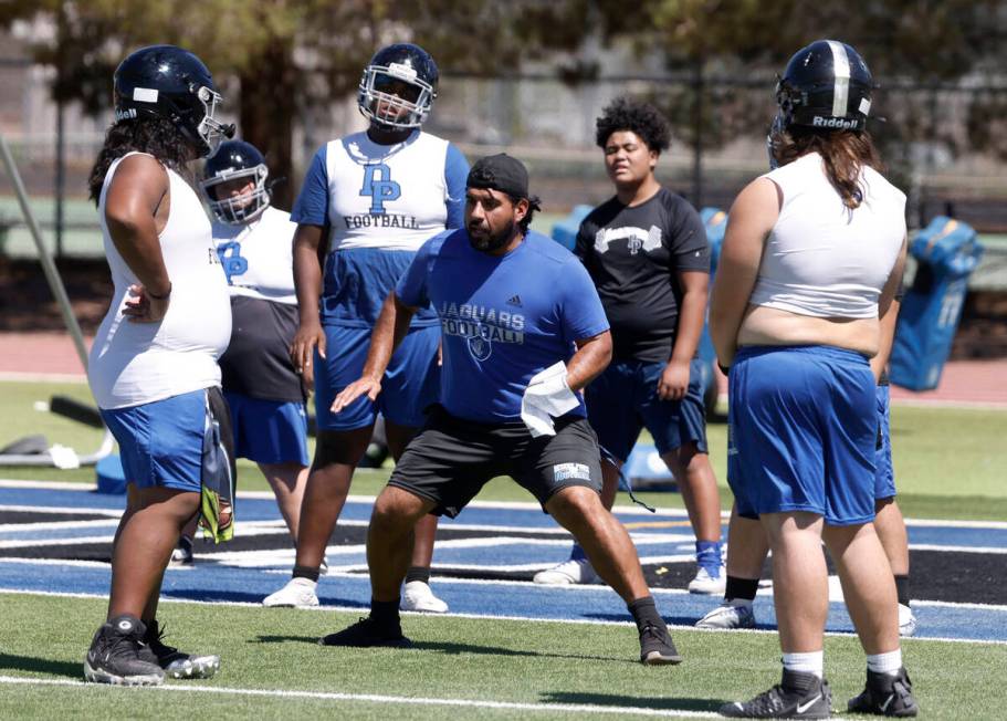 Desert Pines players watch as head coach Jose Flores demonstrates defensive drills during the f ...