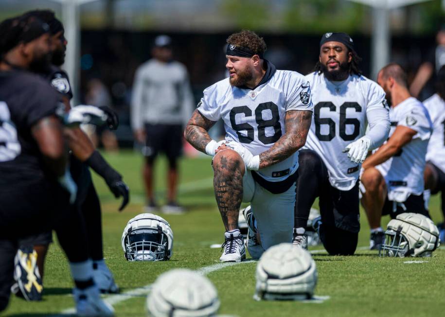 Raiders center Andre James (68) and guard Dylan Parham (66) join teammates in stretching during ...