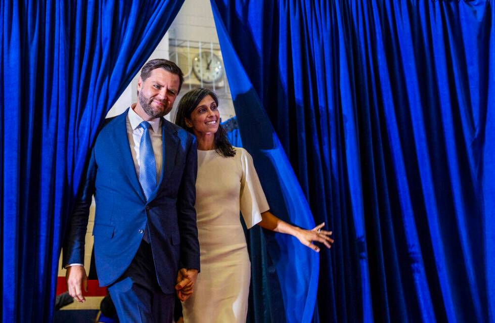 Ohio Senator JD Vance and his wife Usha look out from the side curtains as they arrive on stage ...