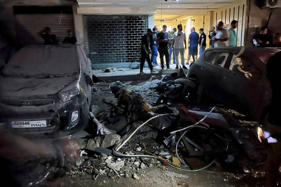 People inspect damaged cars in the southern suburbs of Beirut, Lebanon, Tuesday, July 30, 2024. ...