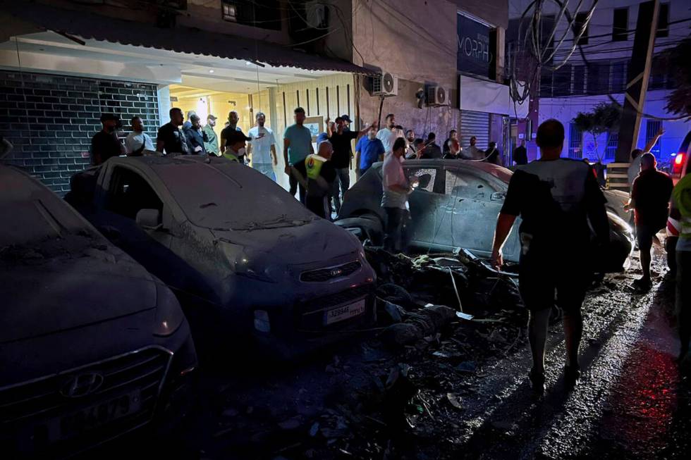 People inspect damaged cars in the southern suburbs of Beirut, Lebanon, Tuesday, July 30, 2024. ...