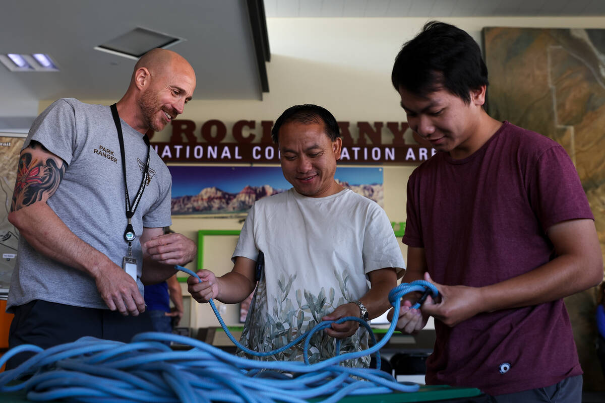 Park ranger Jason Futterer, left, shows Chue Moua and his son Christian Moua, of California, ho ...