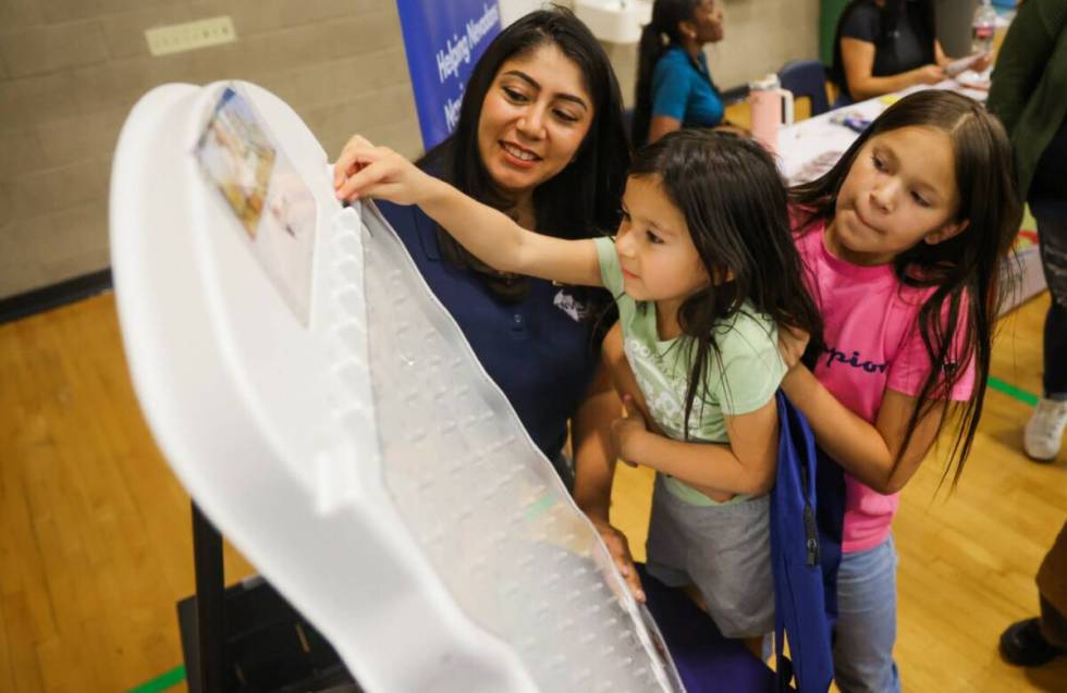 Aria Laroque, 10, lifts Rielle Laroque, 5, up so that she can play a game during a back to scho ...