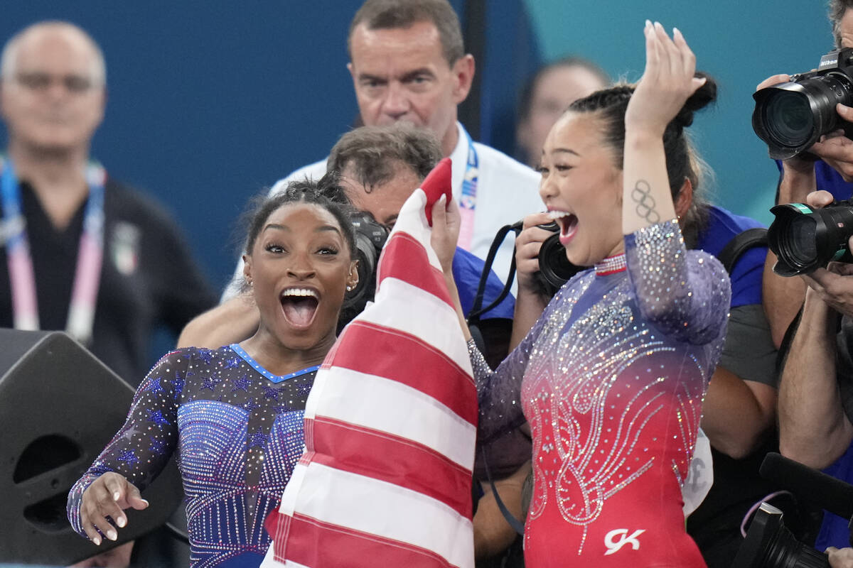 Simone Biles, left, celebrates with teammate Suni Lee, of the United States, after winning the ...