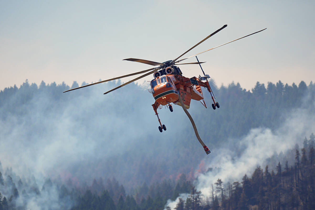 A helicopter heads in for a water drop as the Quarry wildfire burns in the foothills near the K ...