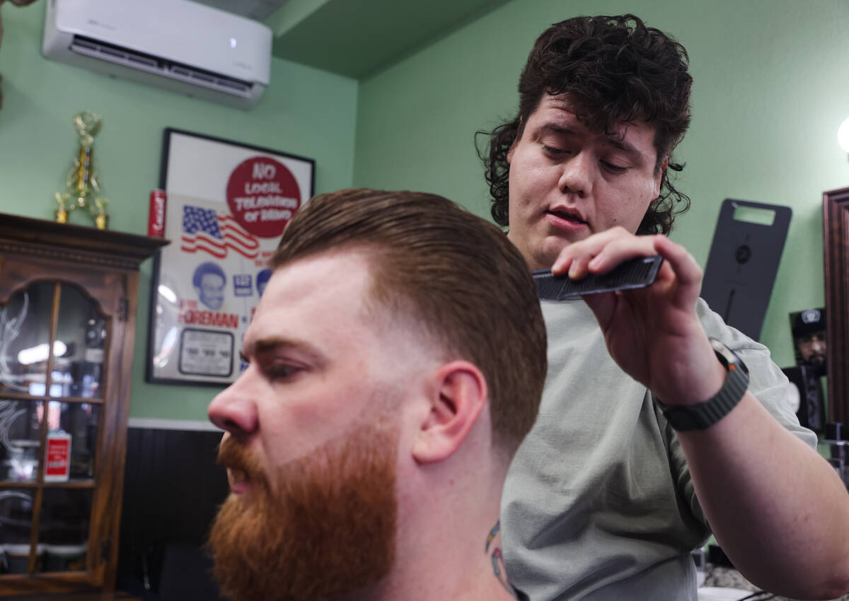 Cesar Reyes, barber and manager, cuts the hair of fellow barber John Hasler while speaking to t ...