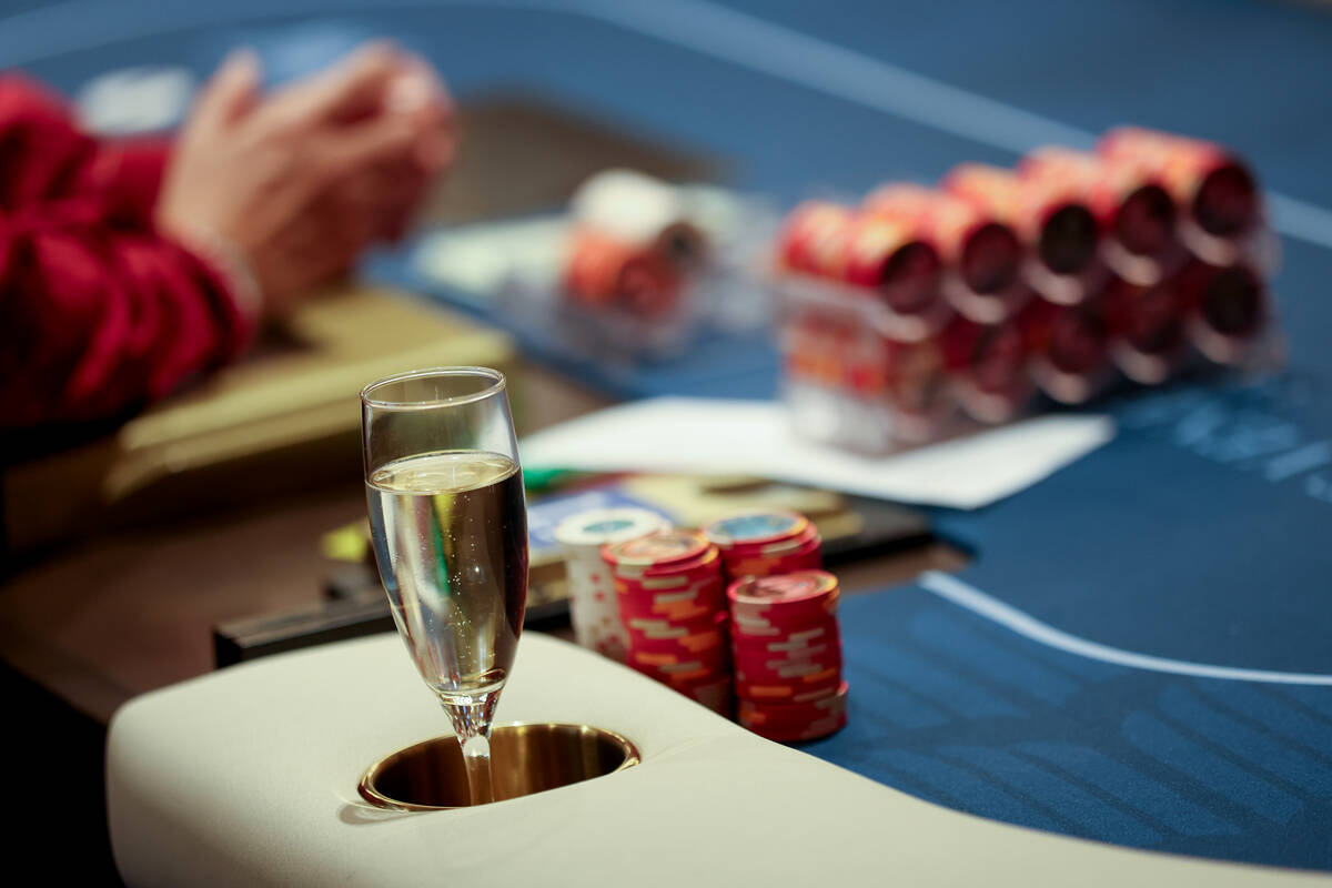 A glass of champagne sits in a drink holder during an opening event for a new poker room in the ...