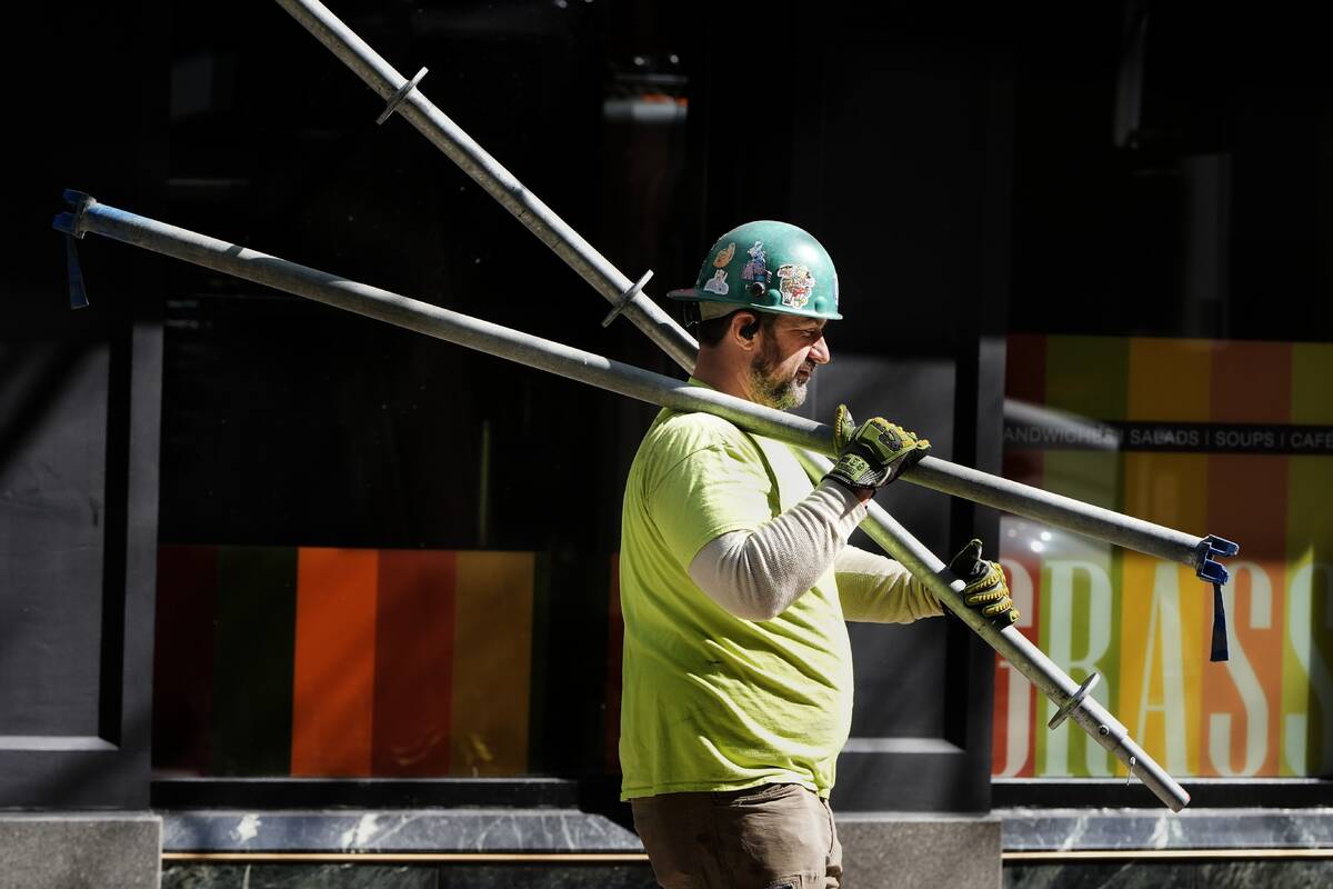 FILE - A construction worker carries scaffolding parts on March 14, 2024, in Boston. On Friday, ...