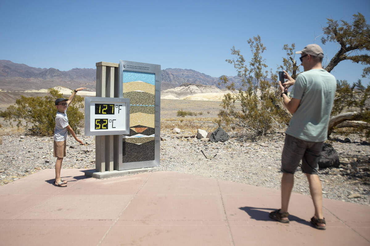 Tourists take photographs in front of the Furnace Creek Visitor Center thermometer on July 8, 2 ...