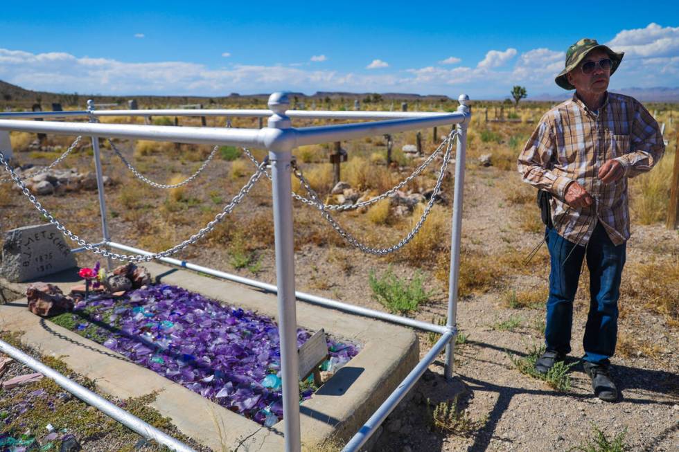 Goldfield resident Allen Metscher stands next to his grandfather’s grave with dousing rods in ...