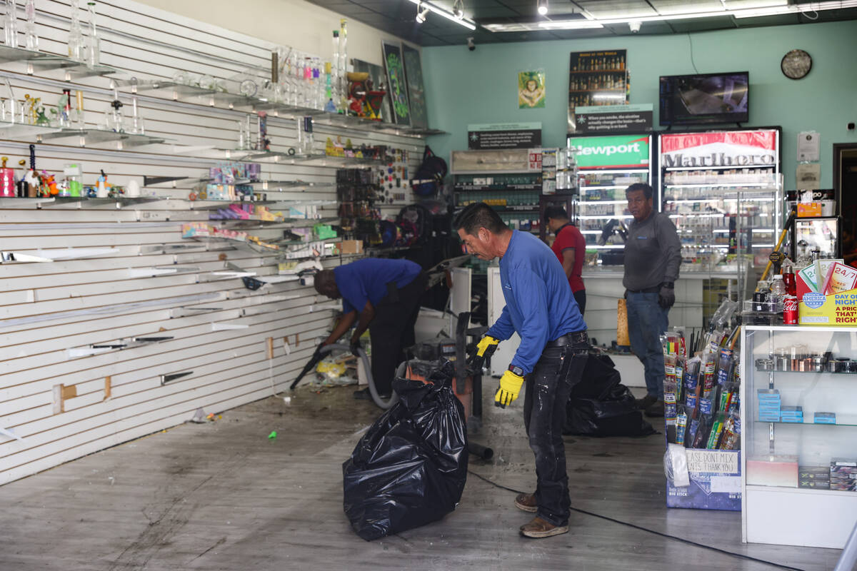 Workers clean up debris in one of the two businesses that two cars reportedly drove into early ...