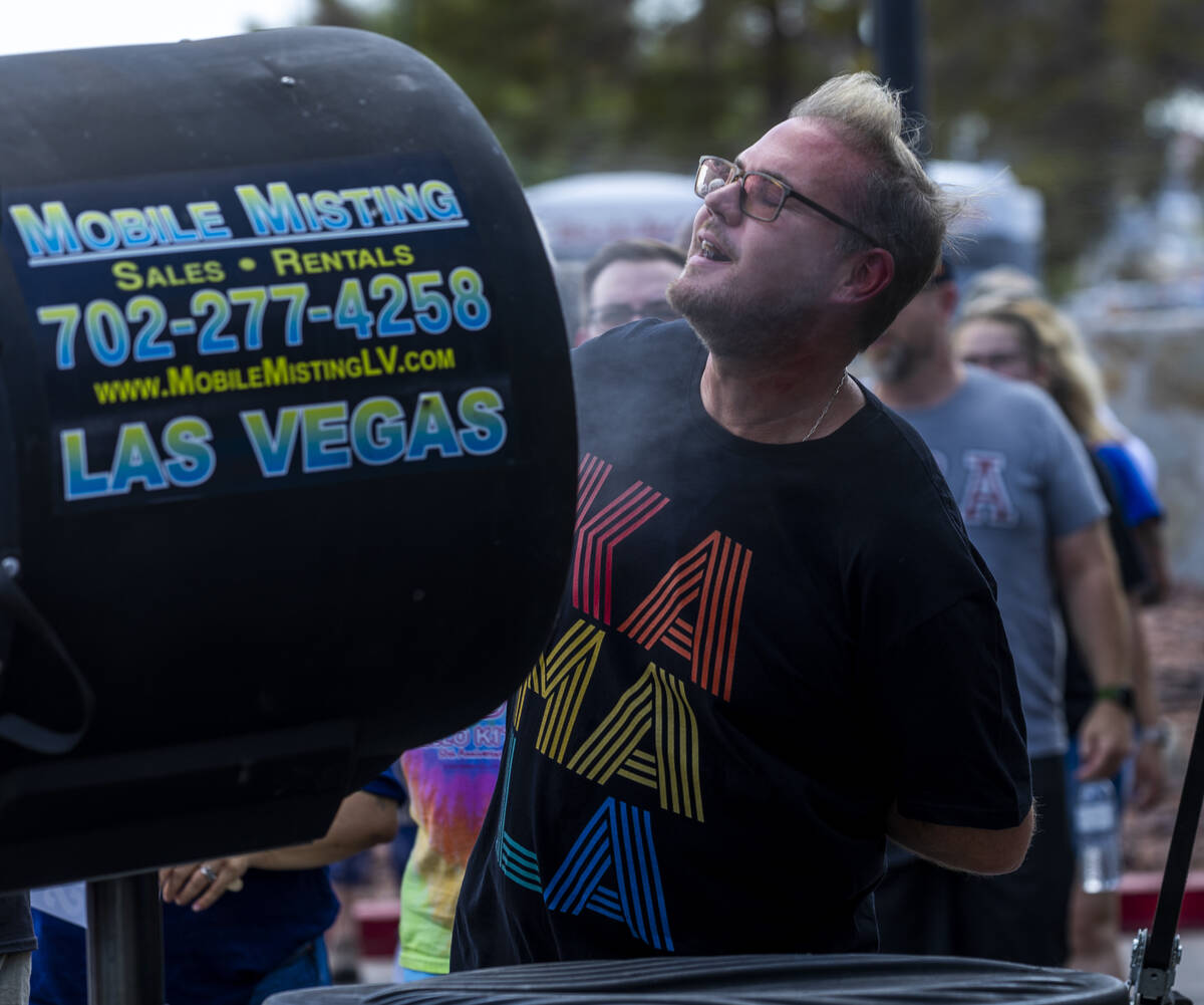 Attendees sneak a quick misting while waiting in the sun to be screened for entry as Vice Presi ...