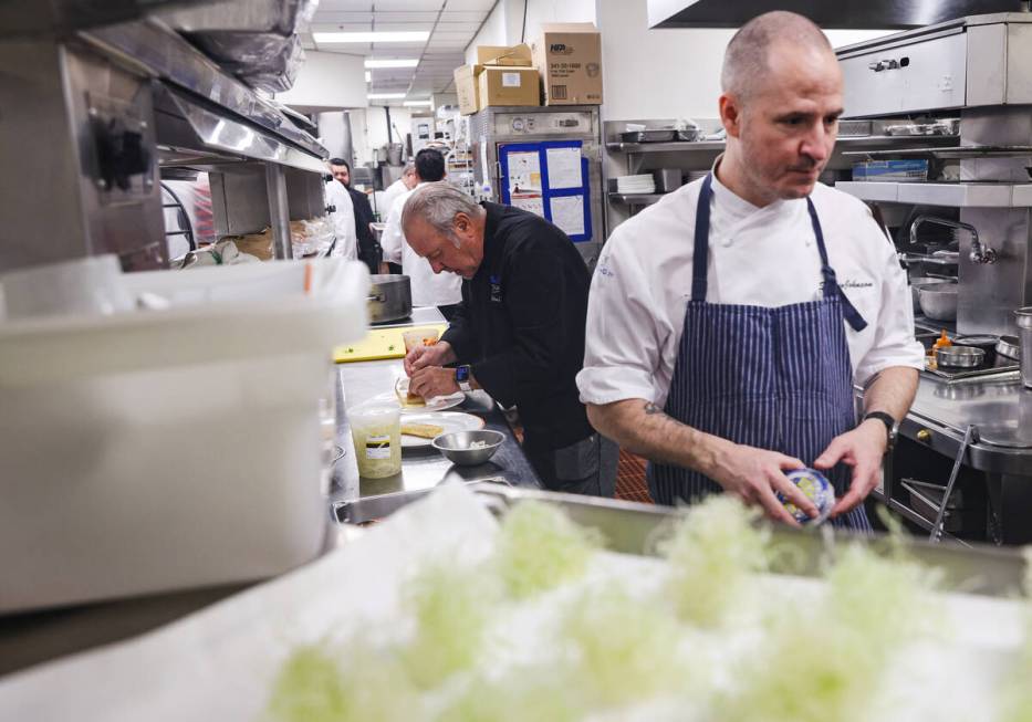 Chef Julian Serrano, left, prepares dishes next to chef Stephen Johnson, right, in the kitchen ...