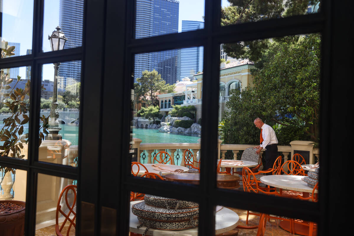 Server Ryland Worrell prepares outdoor seating for dinner service at Picasso at the Bellagio ho ...