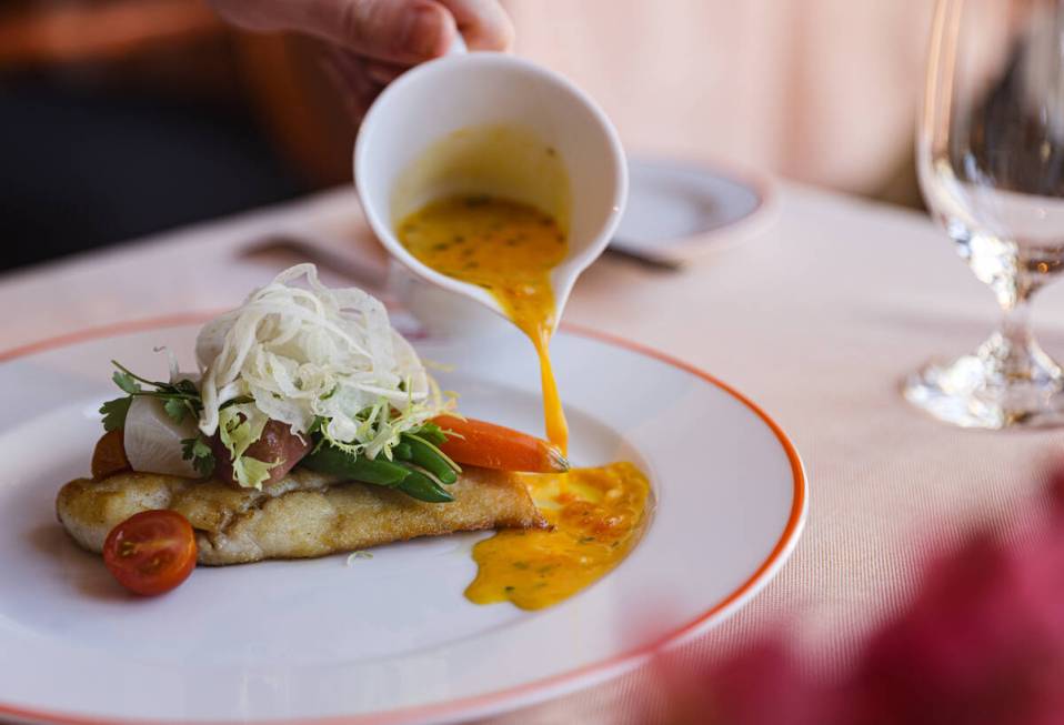 Chef Stephen Johnson spoons court bouillon sauce on the sautéed fillet of branzino at Picasso ...