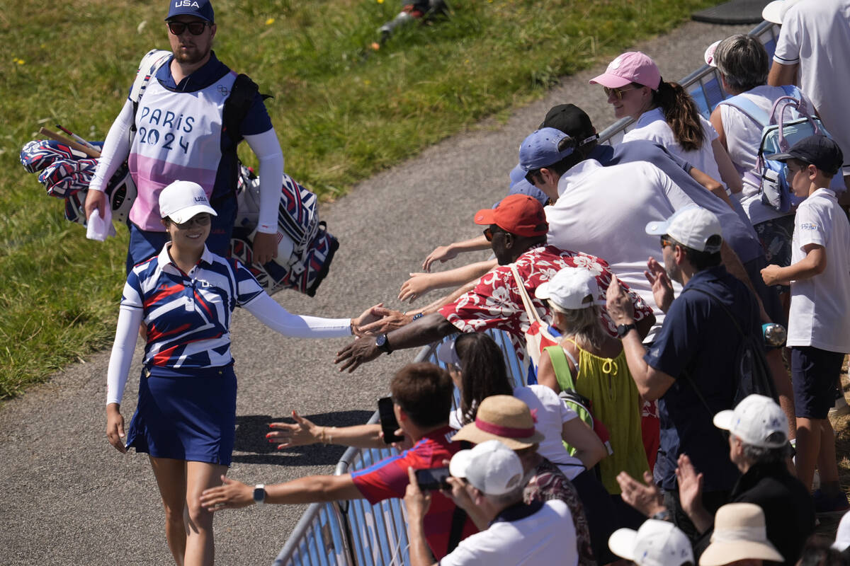 Rose Zhang, of the United States, taps hands with fans as she walks to the 1st tee during the f ...