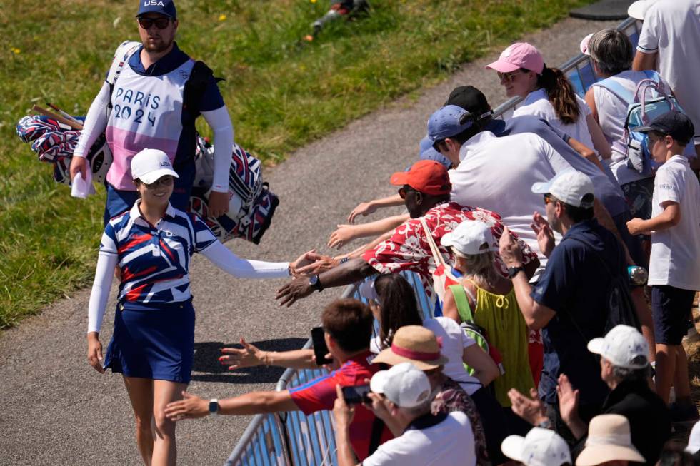 Rose Zhang, of the United States, taps hands with fans as she walks to the 1st tee during the f ...