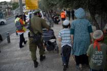 An Israeli soldier pushes a baby stroller as he carries his weapon outside Jerusalem's Old City ...