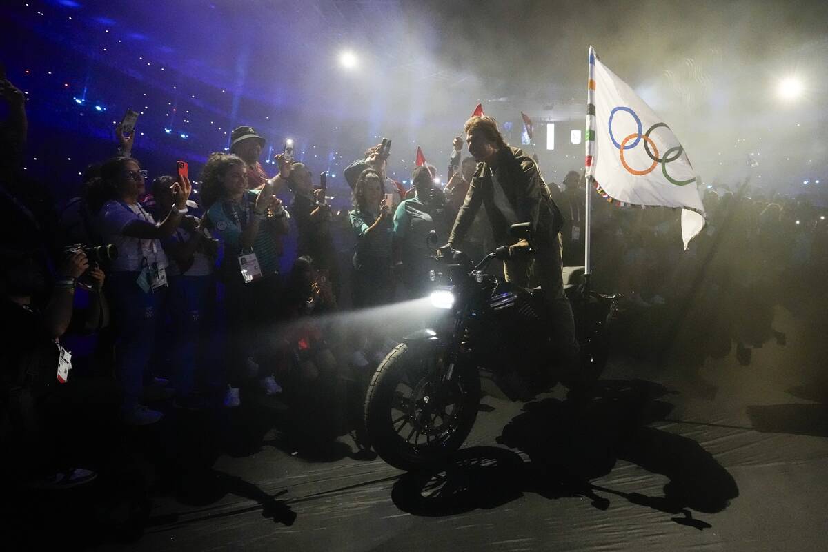 Tom Cruise rides a motorbike with the Olympic flag attached during the 2024 Summer Olympics clo ...