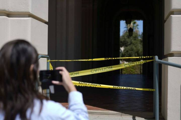 A passerby takes a photo of police caution tape closing off a part of Pasadena City Hall on Mon ...