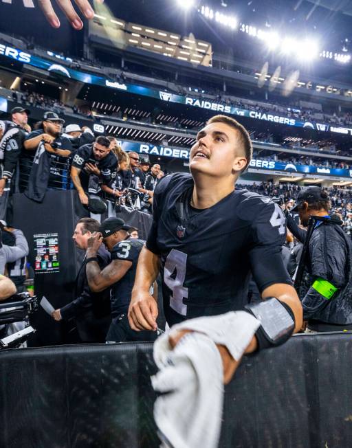 Raiders quarterback Aidan O'Connell (4) looks to toss a fan a towel after defeating the Los Ang ...