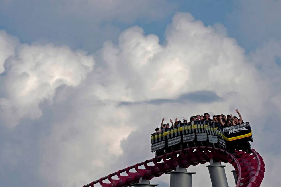 FILE - People ride on the Mamba roller coaster at Worlds of Fun theme park as storm clouds buil ...