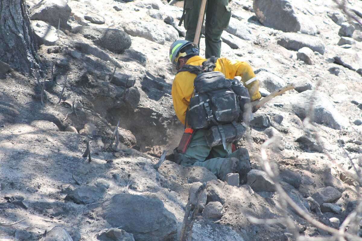 This undated photos shows fire crews working to clear and uproot unburned vegetation that could ...