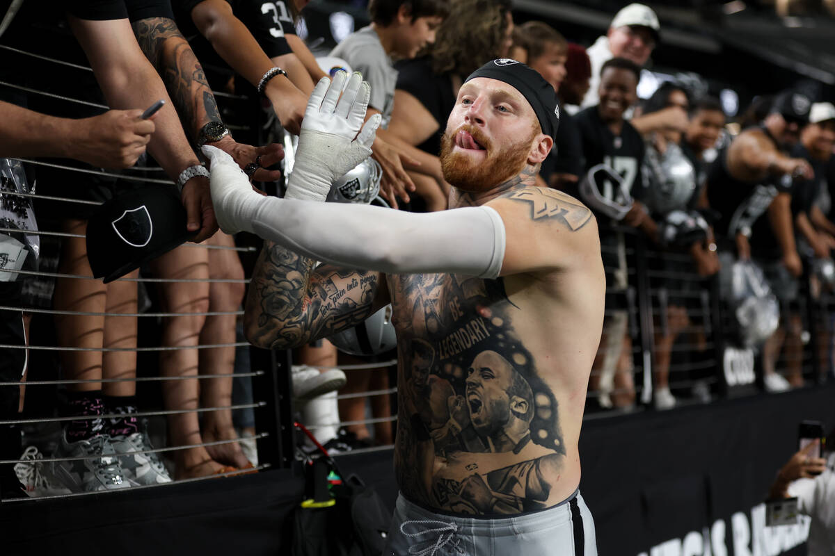 Raiders defensive end Maxx Crosby high-fives fans after an NFL football practice at Allegiant S ...