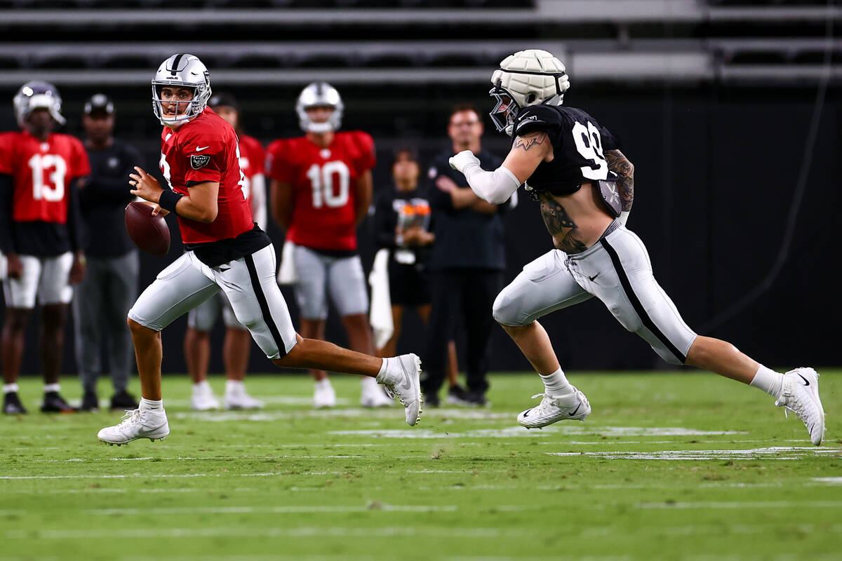 Raiders quarterback Aidan O'Connell (12) looks for an opening to pass while defensive end Maxx ...