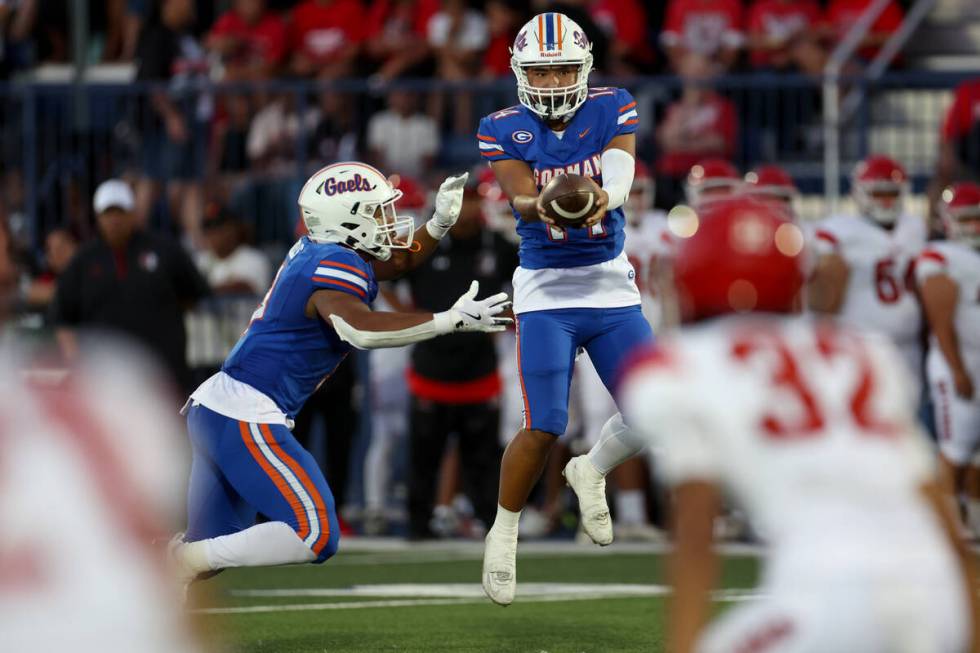 Bishop Gorman quarterback Maika Eugenio, center, hands the ball off to Bishop Gorman running ba ...