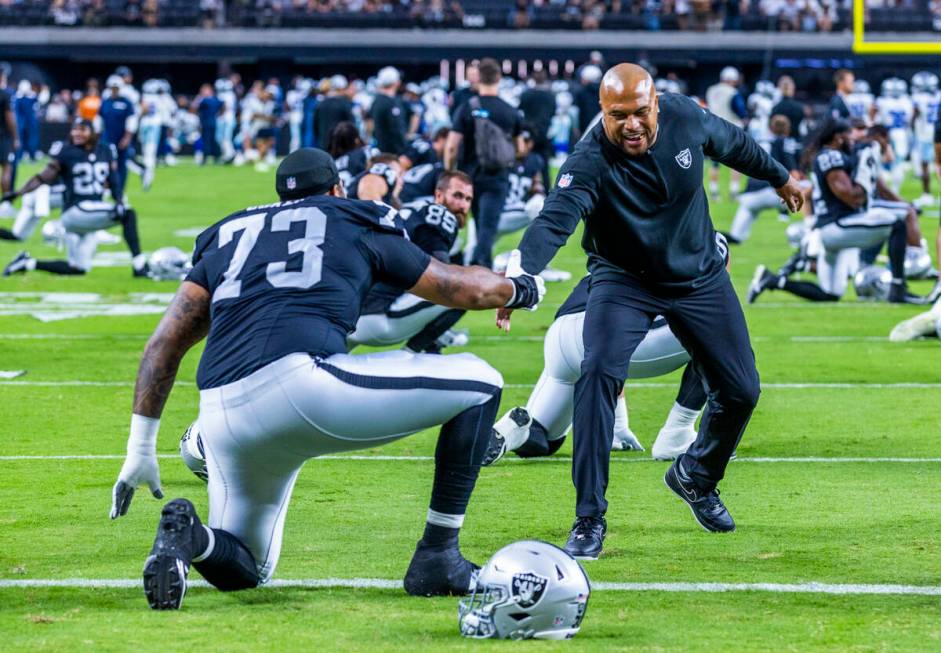 Raiders head coach Antonio Pierce greets offensive tackle Andrew Coker (73) during warm ups bef ...