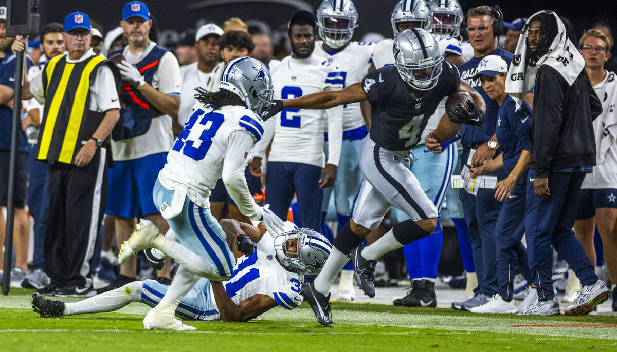 Raiders wide receiver Jalen Guyton (4) breaks a tackle attempt on the sidelines by Dallas Cowbo ...