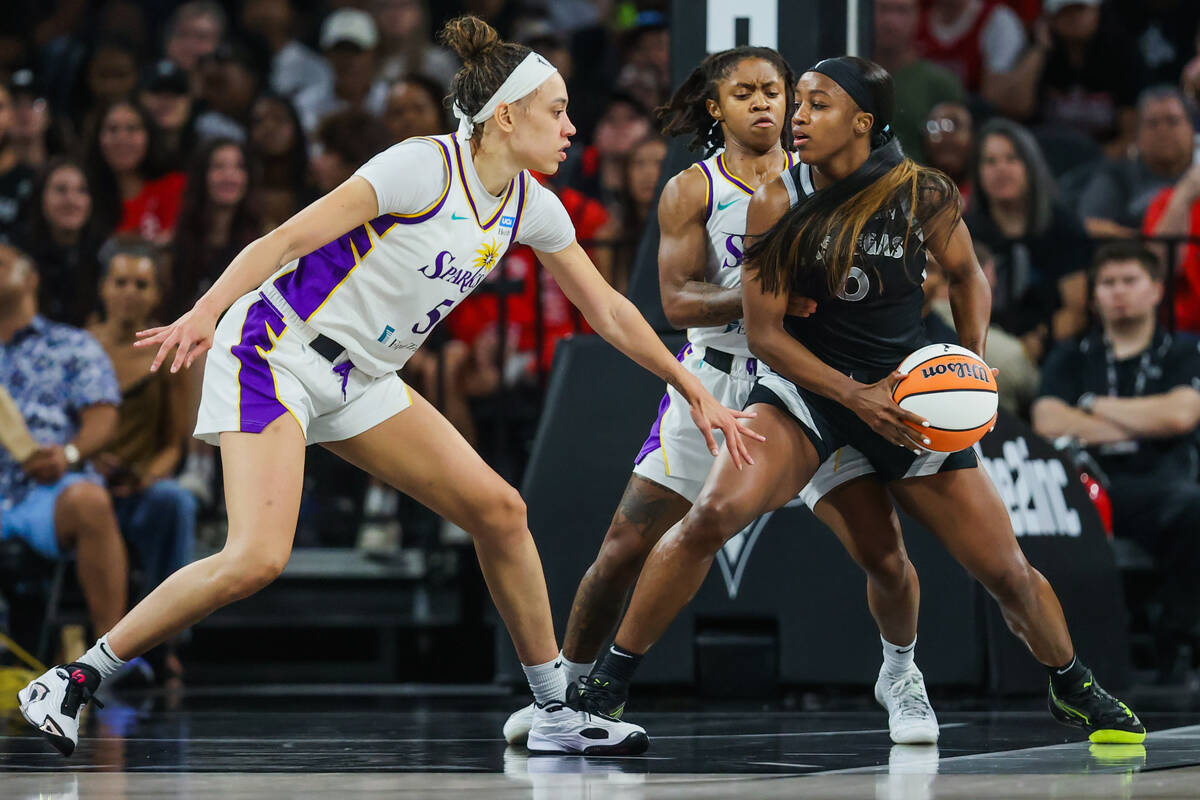 Aces guard Jackie Young (0) moves the ball from Los Angeles Sparks forward Dearica Hamby (5) du ...